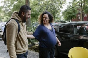 adults-expectant-mother A friend wishes an expectant mother well as she prepares to take a ride in the vehicle parked at the curb.