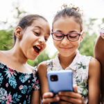 Young girls crowd around a smartphone and share in a special moment.