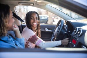 teen-driver-with-mom A teen driver is pictured here smiling at her mother as she prepares to start the car.