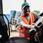 A workplace truck driver smiles as he prepares to hop in the cab and head out on a delivery.